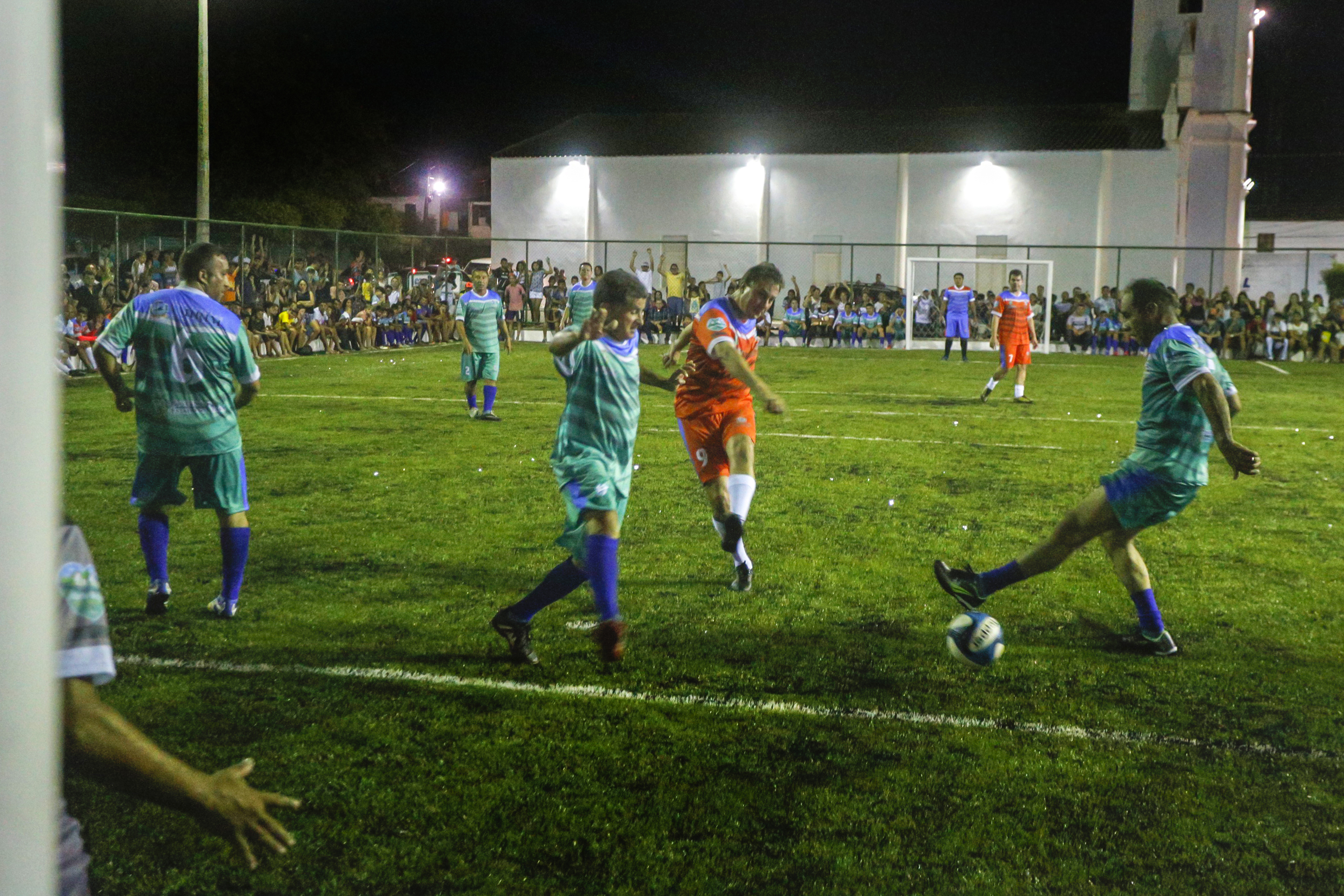 Governador Camilo Santana participa de partida inaugural da Areninha de Umirim. Na foto, um momento da partida em que o governador tenta chute ao gol cercado por jogadores do time adversário